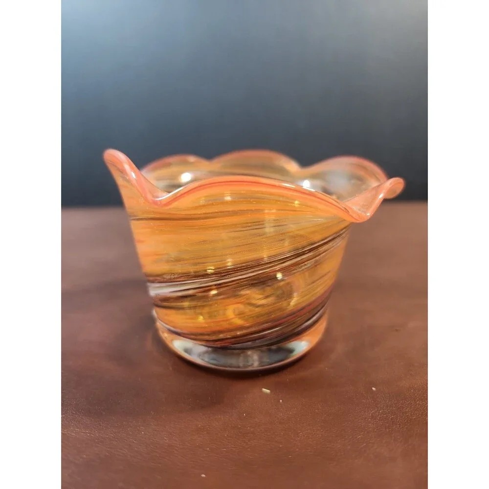 hand-blown art glass bowl features a vibrant orange and amber swirl pattern with